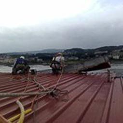 Retirada de un perfil de aluminio suspendido en la fachada a causa de un temporal, Oleiros (A Coruña)