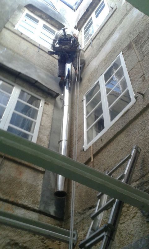 Trabajador colocando salida de humos en fachada de patio interior de edificio