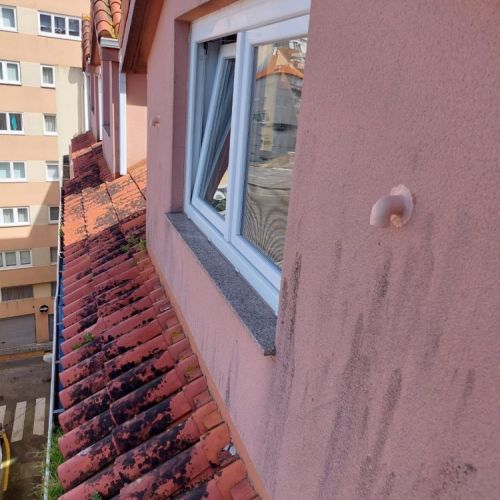 Ventana en fachada de edificio con tubos blancos de salida de humos