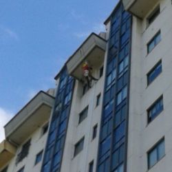 Trabajador colocando bajante en fachada de edificio