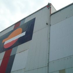 Imagen de fachada de nave de Repsol con lona grande con logotipo