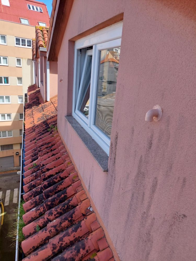 Ventana en fachada de edificio con tubos blancos de salida de humos