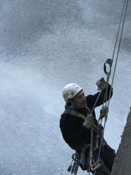 Primer plano de trabajador colgado el altura con arneses en pared de presa