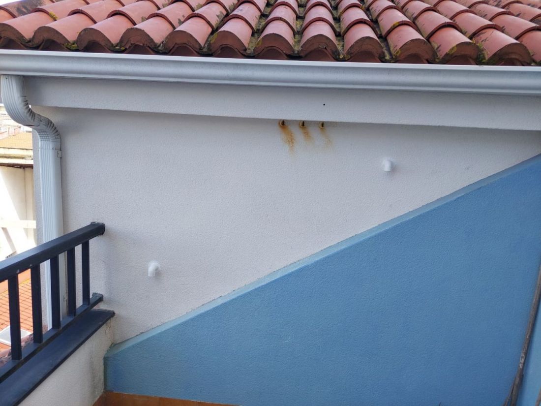 Imagen de tubo rectangular de color blanco en salida de humos junto a tejado