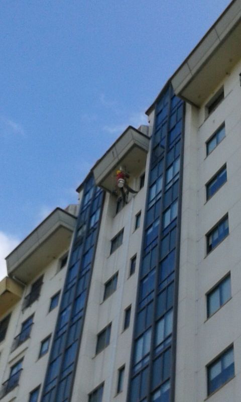 Trabajador colocando bajante en fachada de edificio