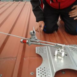 Imagen de trabajador tensando el cable de una línea de vida colocada en tejado